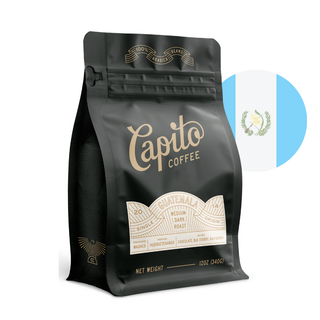 A black, resealable 12oz coffee bag labeled "Capito Coffee" with gold lettering, indicating it is a single-origin, medium dark roast from Guatemala. The bag features a sleek design with illustrated coffee beans. The flag of Guatemala is in the background.