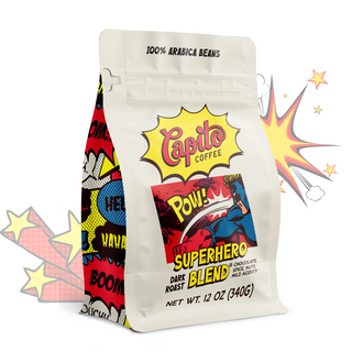 A 12 oz (340g) bag of Capito Coffee's "Superhero Blend" is displayed. The packaging features vibrant, comic-style graphics with playful exclamations like "Pow!" and "Boom." This bold and strong dark roast coffee boasts notes of chocolate, spice, and mild acidity.